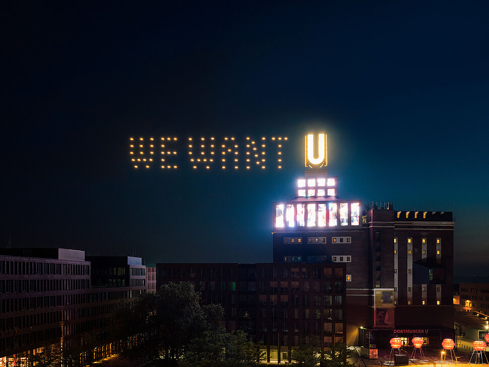 Leuchtender "WE-WANT-U"-Schriftzug am Dortmunder U bei Nacht