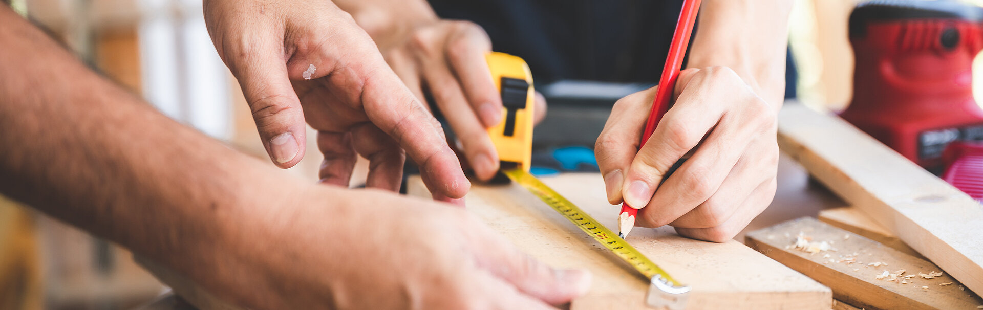 Hände von Handwerkerinnen und Handwerker bei der Schreinerarbeit.