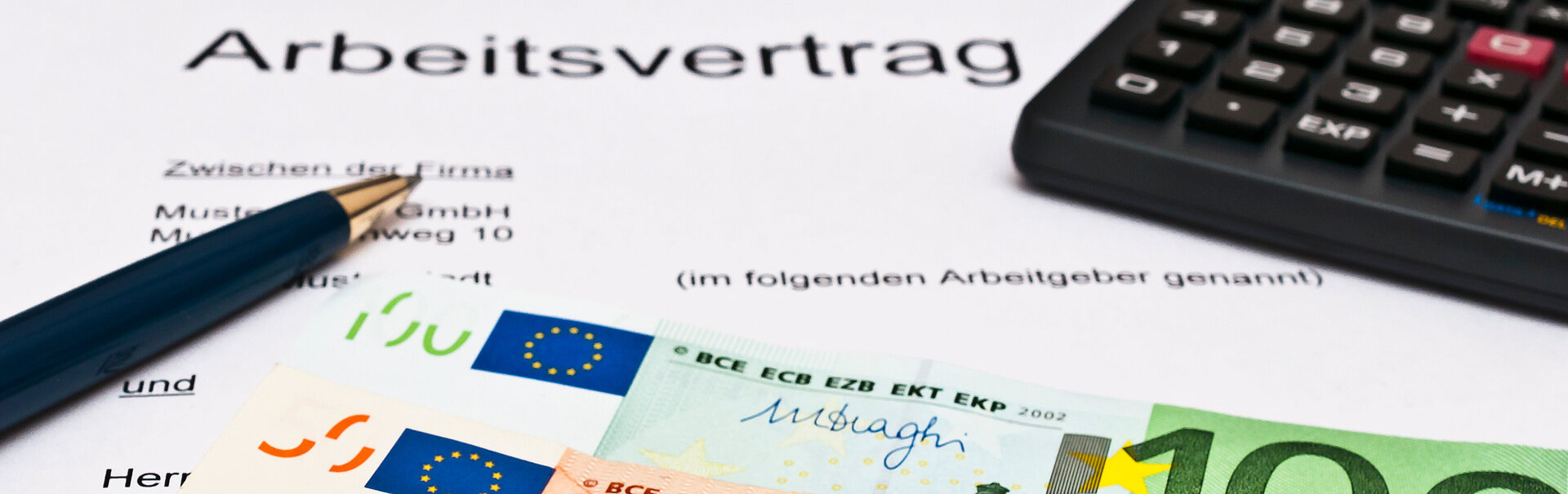 Geldmünzen, Geldscheine, ein Stift, ein Taschenrechner und ein Arbeitsvertragsdokument
